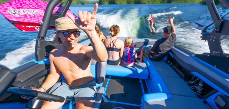 T220 Wake suref wakeboard boat to rent showing family enjoy lake while a kid surfs